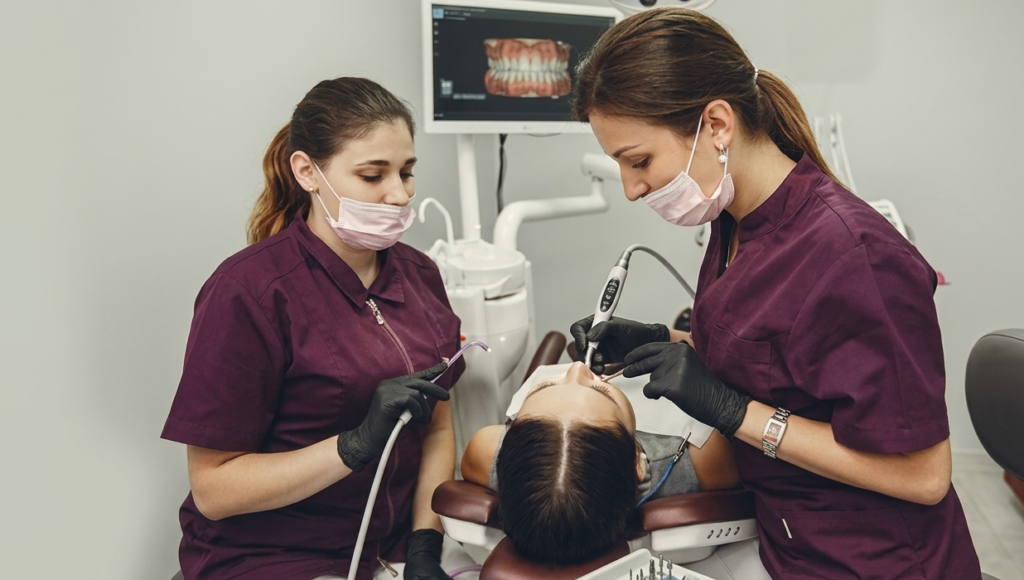 Dental assistants assisting a patient chairside dental assistant jobs.