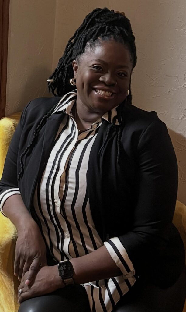 Tishabu Nicks, Stautzenberger College Medical Assistant alumna and ProMedica Office Manager, smiling while seated in a black blazer and striped blouse.