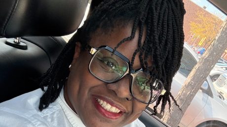 Tishabu Nicks, a 2009 Stautzenberger College Medical Assistant graduate, smiling in glasses and a white blouse while seated in a car.