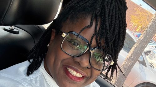 Tishabu Nicks, a 2009 Stautzenberger College Medical Assistant graduate, smiling in glasses and a white blouse while seated in a car.